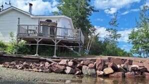 A house with a balcony and a rocky shoreline. - Skipper's View Cottage by the Sea - Pet Friendly! (Point Leamington)