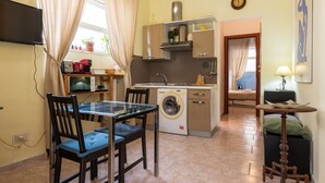 Une cuisine compacte comprenant un lave-linge, une table à manger avec des chaises et une petite table avec une lampe.