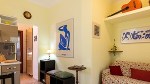 Un salon avec un canapé, une table basse en verre, une lampe et des œuvres d’art accrochées aux murs.
