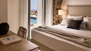 Een hotelkamer met een bed, een tafel met een boek, een lamp en uitzicht op zee.