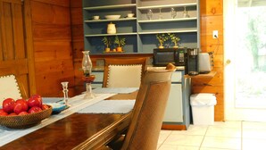 A wooden interior with a dining table set for two, a microwave, and a coffee maker.