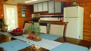 A wooden-paneled kitchen with cabinets, a refrigerator, and a dining table with placemats.