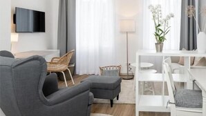 A modern living room with a grey sofa, white coffee table, and a chandelier. - Hotel Markt 5 (Lubbecke)