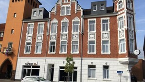 A historic building with a prominent clock tower, a shop named 'KUPERS' on the ground floor, and a sign for 'MARKET' on the right. - Hotel Markt 5 (Lubbecke)
