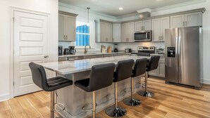Una cocina moderna con una isla central, electrodomésticos de acero inoxidable y una zona de bar con taburetes.