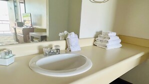 A hotel bathroom with a white sink, a mirror, and a stack of towels. - 2 Queens - 3 Miles to Cedar Point! (Sandusky)
