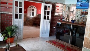 Un amplio espacio de sala con un sofá, una mesa de centro, un televisor y una cocina con mostrador y armarios.