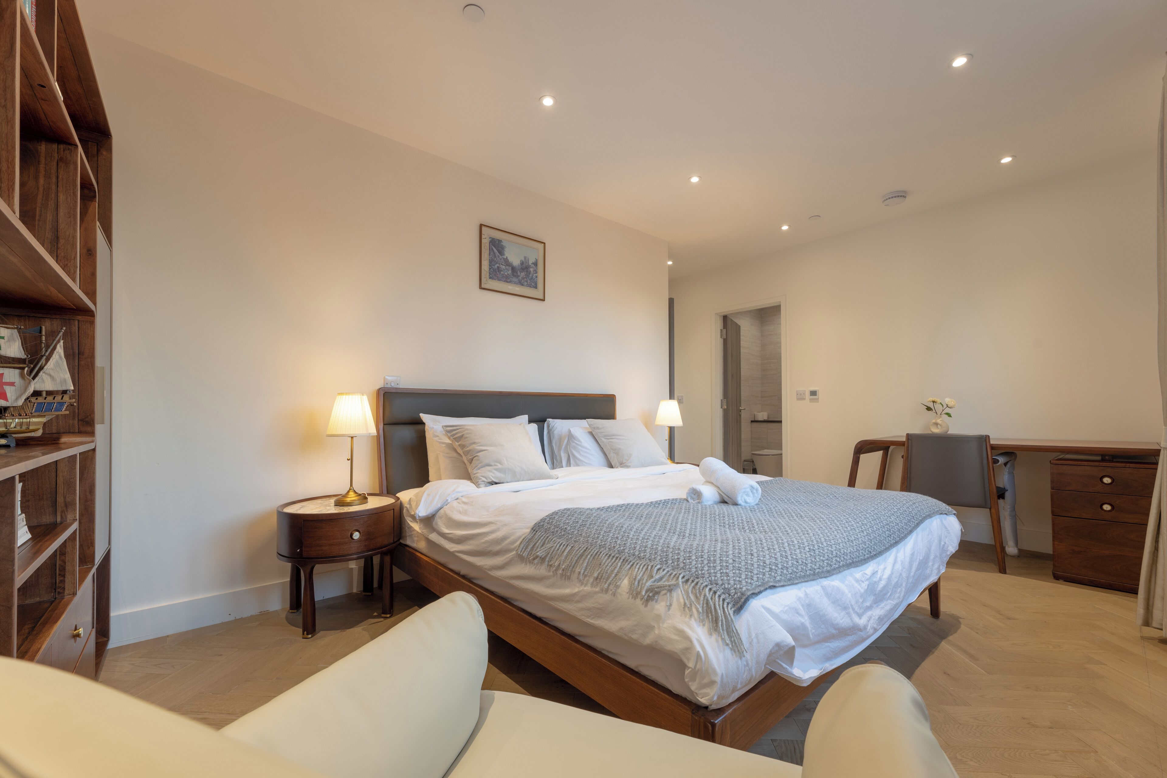 A bedroom with a bed, bedside tables, a desk, and a chair.