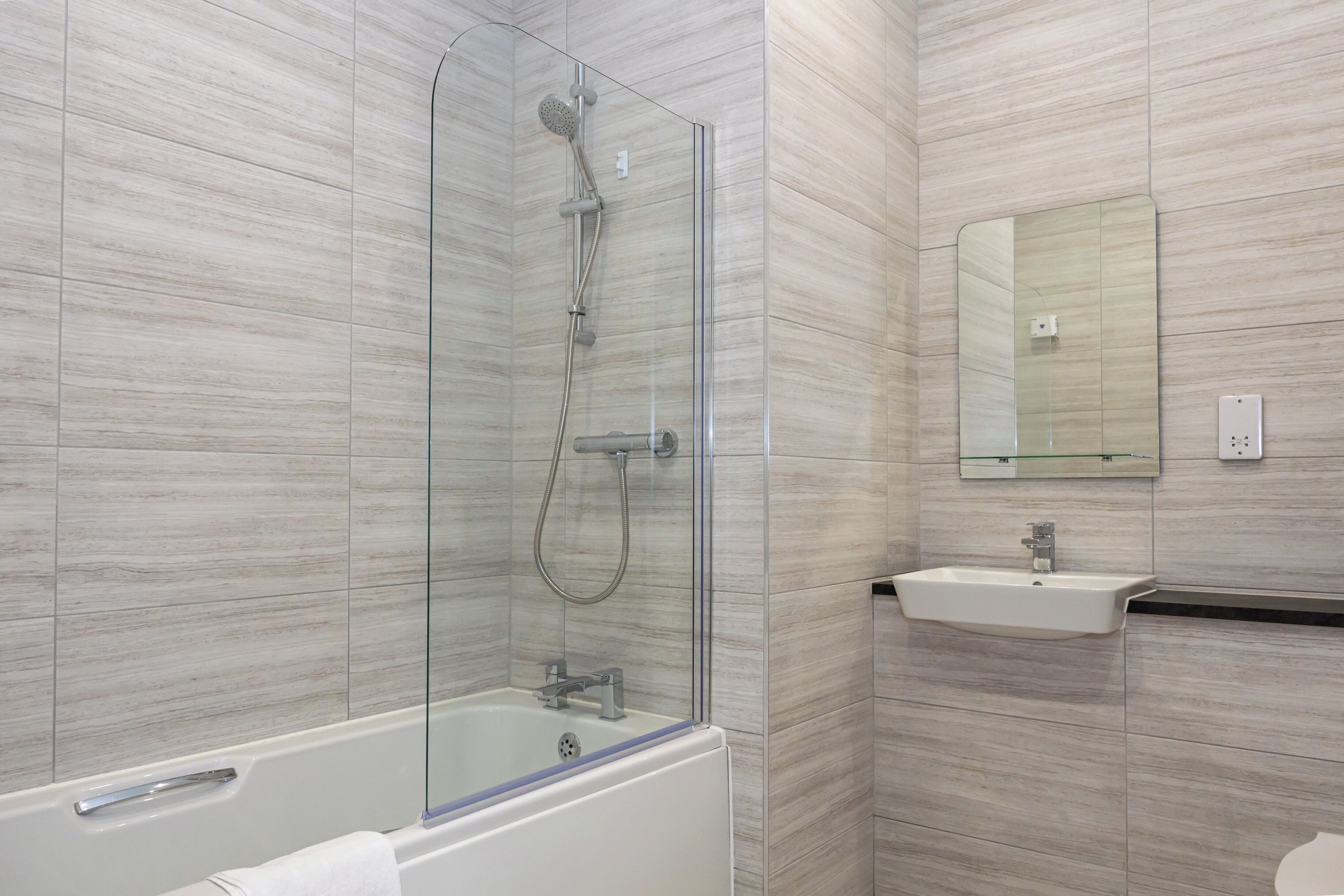Une salle de bain moderne avec une douche à parois de verre, une baignoire blanche et un lavabo surmonté d’un miroir.