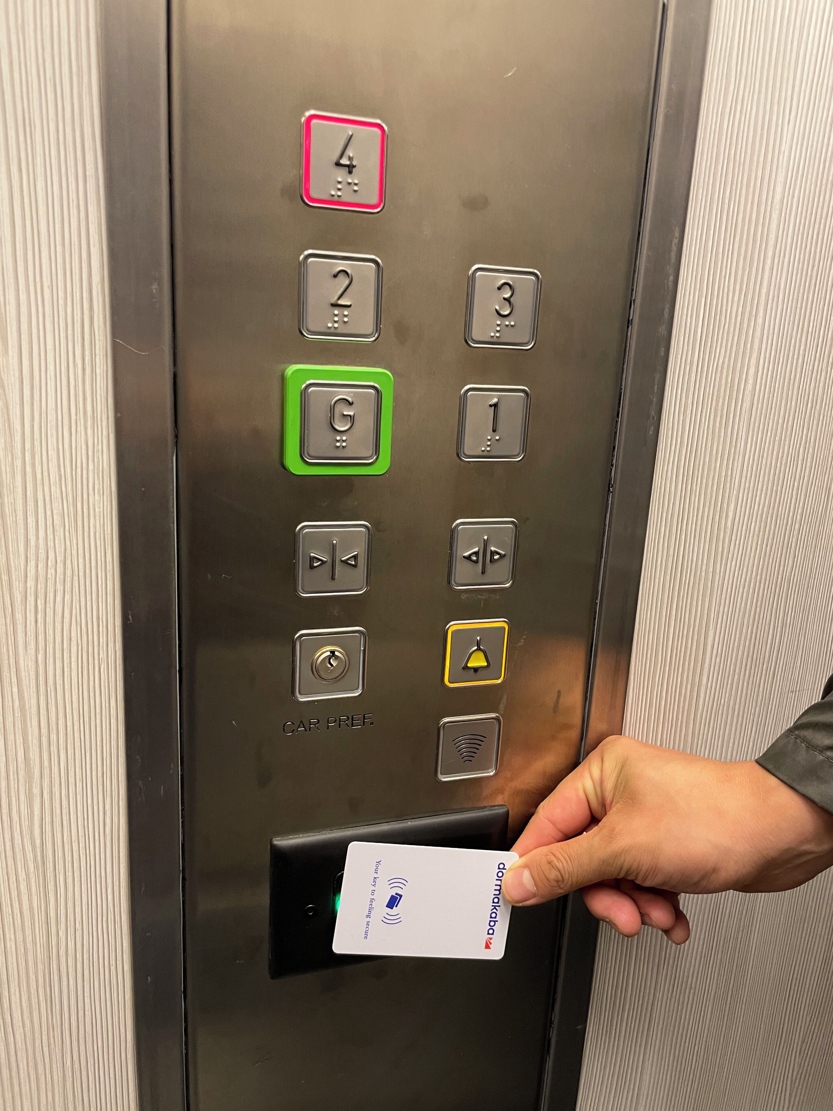 An elevator control panel with numbered buttons, a green 'G' button, and a card reader for a key card.