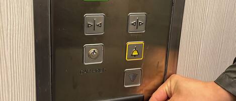 An elevator control panel with numbered buttons, a green 'G' button, and a card reader for a key card.