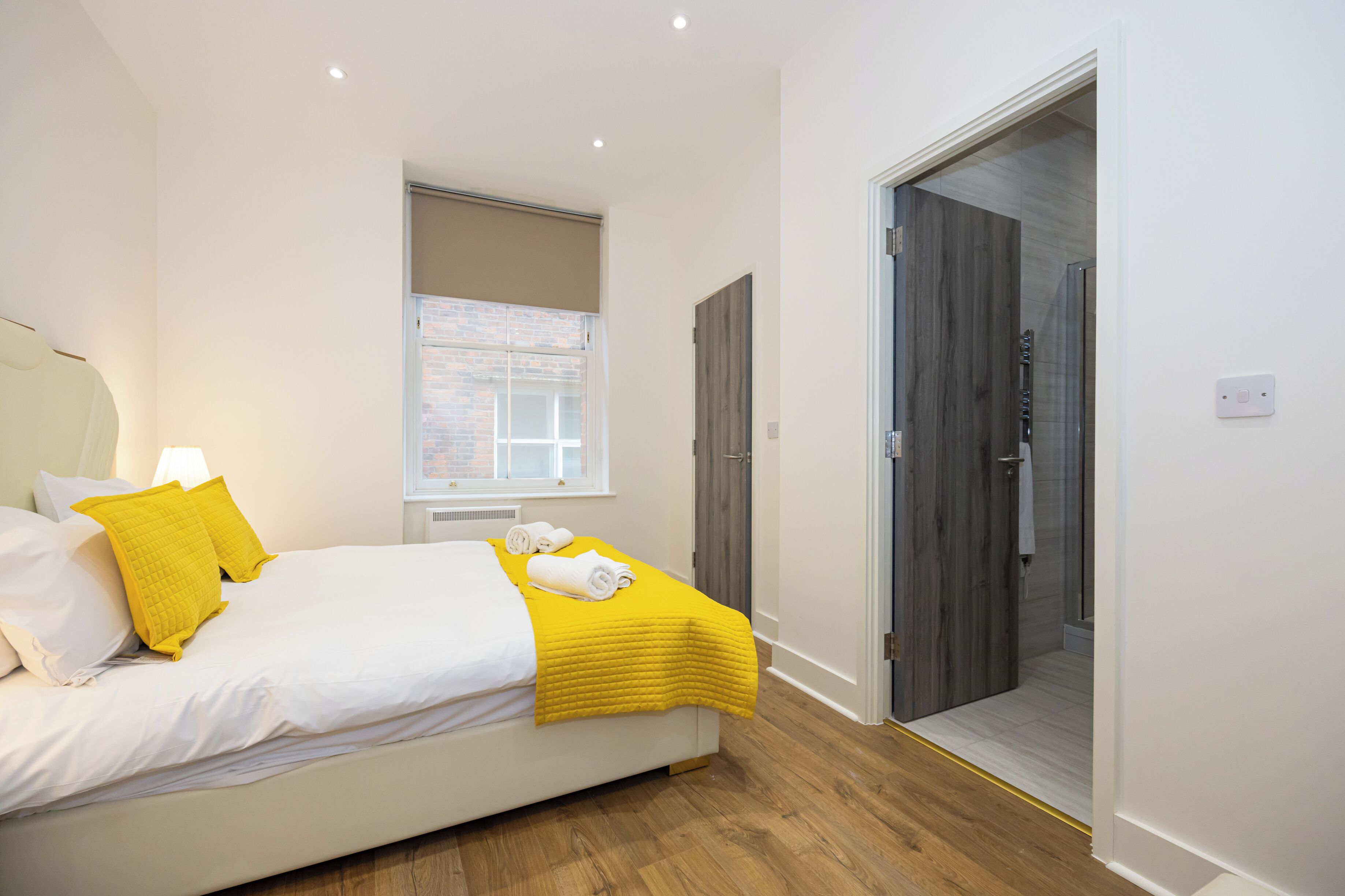 Une chambre à coucher moderne, avec un lit, une fenêtre et une porte donnant sur une salle de bain.
