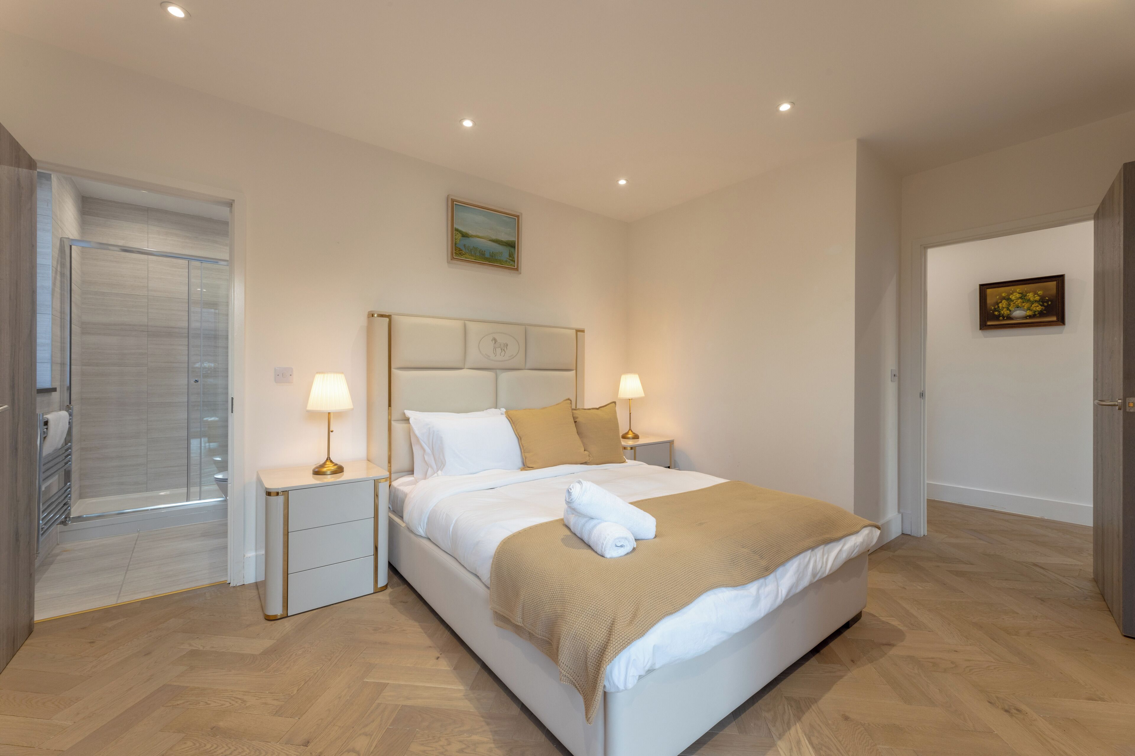 Una camera da letto ordinata con un letto, comodini e una porta che dà su un bagno.