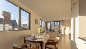 A modern dining area with a table set for four, large windows, and a view of the cityscape. - Orient Residence Manchester (Manchester)