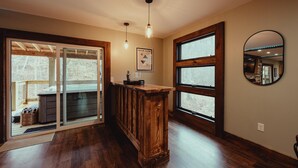 A wooden bar area with a large window, a mirror, and a framed picture on the wall.