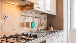 Une cuisine moderne équipée d’une cuisinière à gaz, d’un four et d’appareils électroménagers en acier inoxydable. Une fenêtre offre une vue sur l’extérieur.