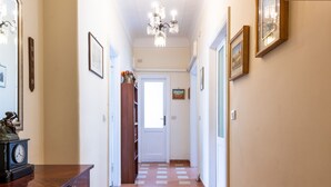 Un couloir avec une table en bois, un lustre et une porte au fond.