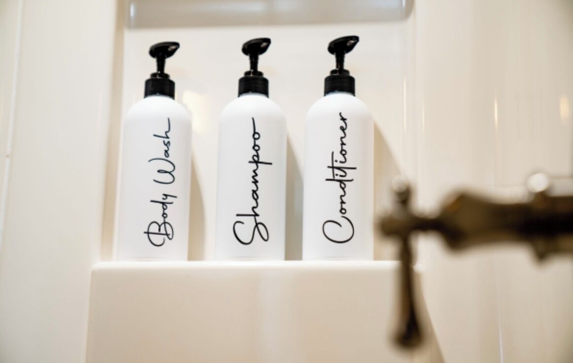 Three bottles of body wash, shampoo, and conditioner in a bathroom cabinet.