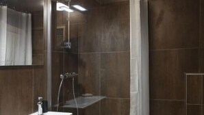 A modern bathroom with a shower, a vanity with a mirror, and a toilet.