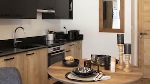 A modern kitchen with dark cabinets, a wooden dining table, and pendant lighting.