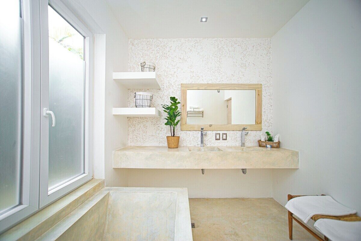 A bathroom with a large window, a sink with a mirror, shelves, and a bench.