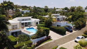 Una zona residencial moderna con varias casas, piscina y abundante vegetación.