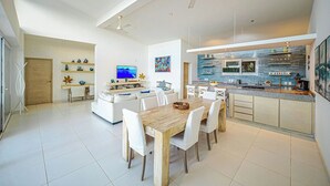 Una cocina moderna con una mesa de comedor de madera, sillas blancas y una isla integrada con asientos.