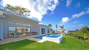 Una casa moderna con piscina, mobiliario exterior y césped cuidado.