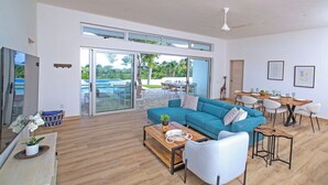 A spacious living area with a blue sofa, wooden coffee table, and a dining table set for six.