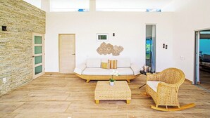 A spacious living area with a stone wall, a sofa, a wicker chair, and a coffee table.
