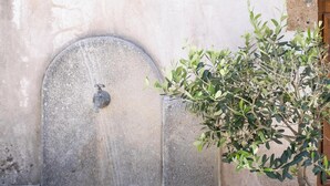 Ein Steinkunstbrunnen mit einer Pflanze daneben.