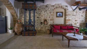 Ein rustikales Interieur mit einer Steinwand, Holzmöbeln und einem roten Sofa.