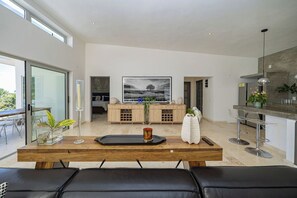 A modern kitchen with a wooden island, a large framed artwork, and a dining area with black leather seating.