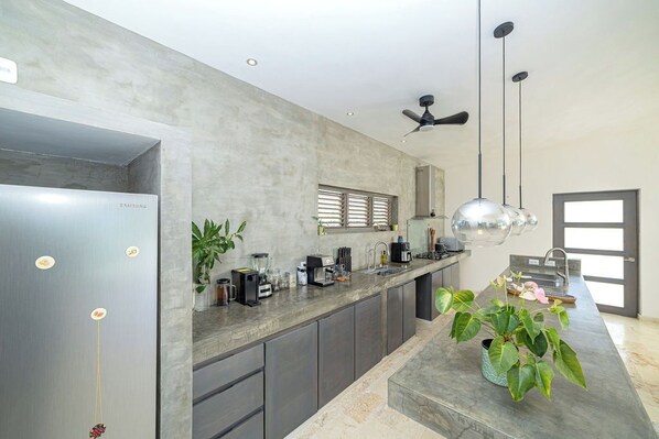 Una cocina moderna con un refrigerador de acero inoxidable, una encimera amplia y un ventilador de techo.