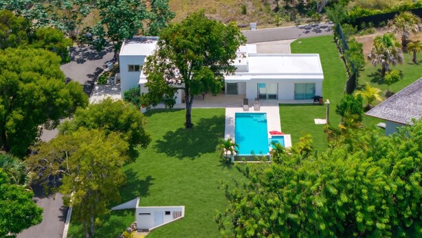 A modern house with a swimming pool, surrounded by lush greenery.