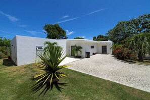 Une maison moderne avec une façade blanche, une allée en gravier et une pelouse bien entretenue.