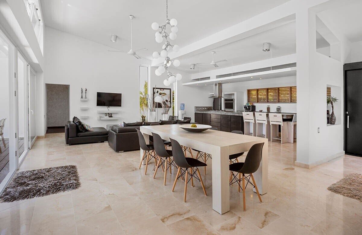 Amplia sala de estar con una mesa de comedor, sofá y cocina al fondo.