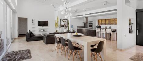 Amplia sala de estar con una mesa de comedor, sofá y cocina al fondo.