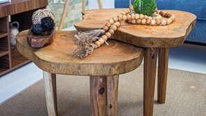 Een houten tafel met een glazen vaas, een houten kralenketting en een decoratieve bal.
