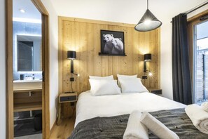 Habitación de hotel con cabecera de madera, cama grande con ropa blanca, dos lámparas de noche y un cuadro enmarcado de osos polares en la pared.