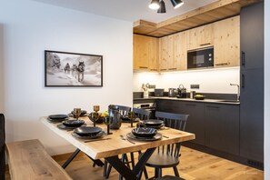 Una cocina moderna con armarios de madera, microondas y comedor con mesa de madera dispuesta para cuatro.