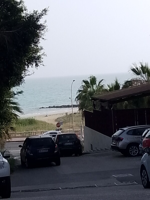 Un área de estacionamiento con coches, una señal de parada y vistas a la playa y el océano.