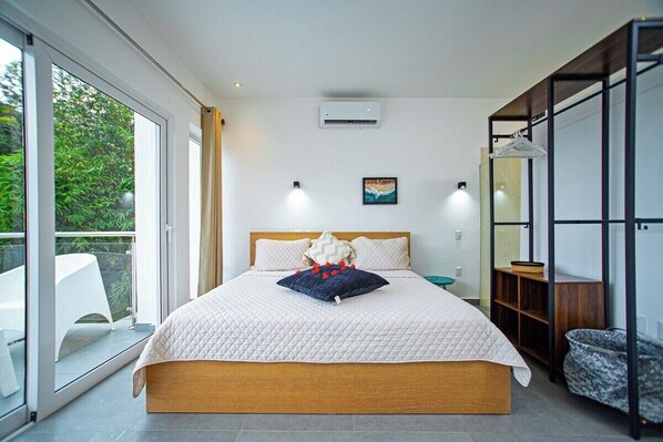 Un dormitorio con una cama grande, una puerta corrediza de vidrio a un balcón y un armario de madera.