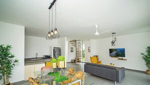 Un salon moderne comprenant un canapé, une table à manger avec des chaises, un coin cuisine et un escalier menant à un autre niveau.