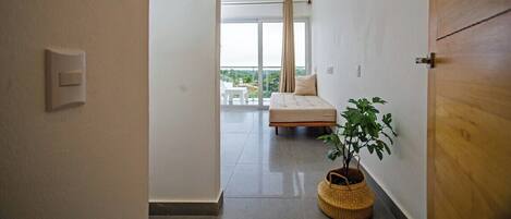 Una habitación de hotel moderna con balcón, una cama, una planta en maceta y una puerta de madera.