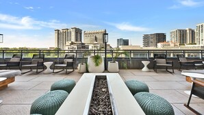 En takterrass med sittplatser, en fontän och utsikt över stadens skyline.
