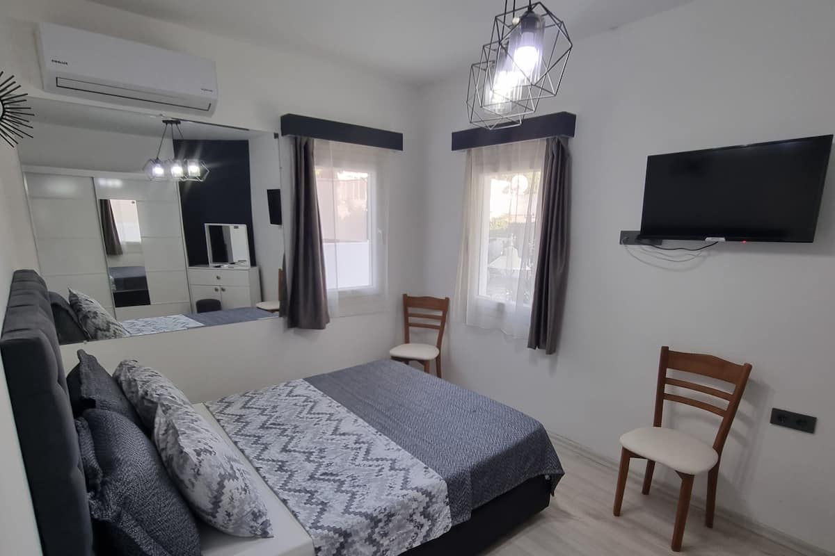 A modern bedroom with a bed, a chair, a TV, and a mirror.