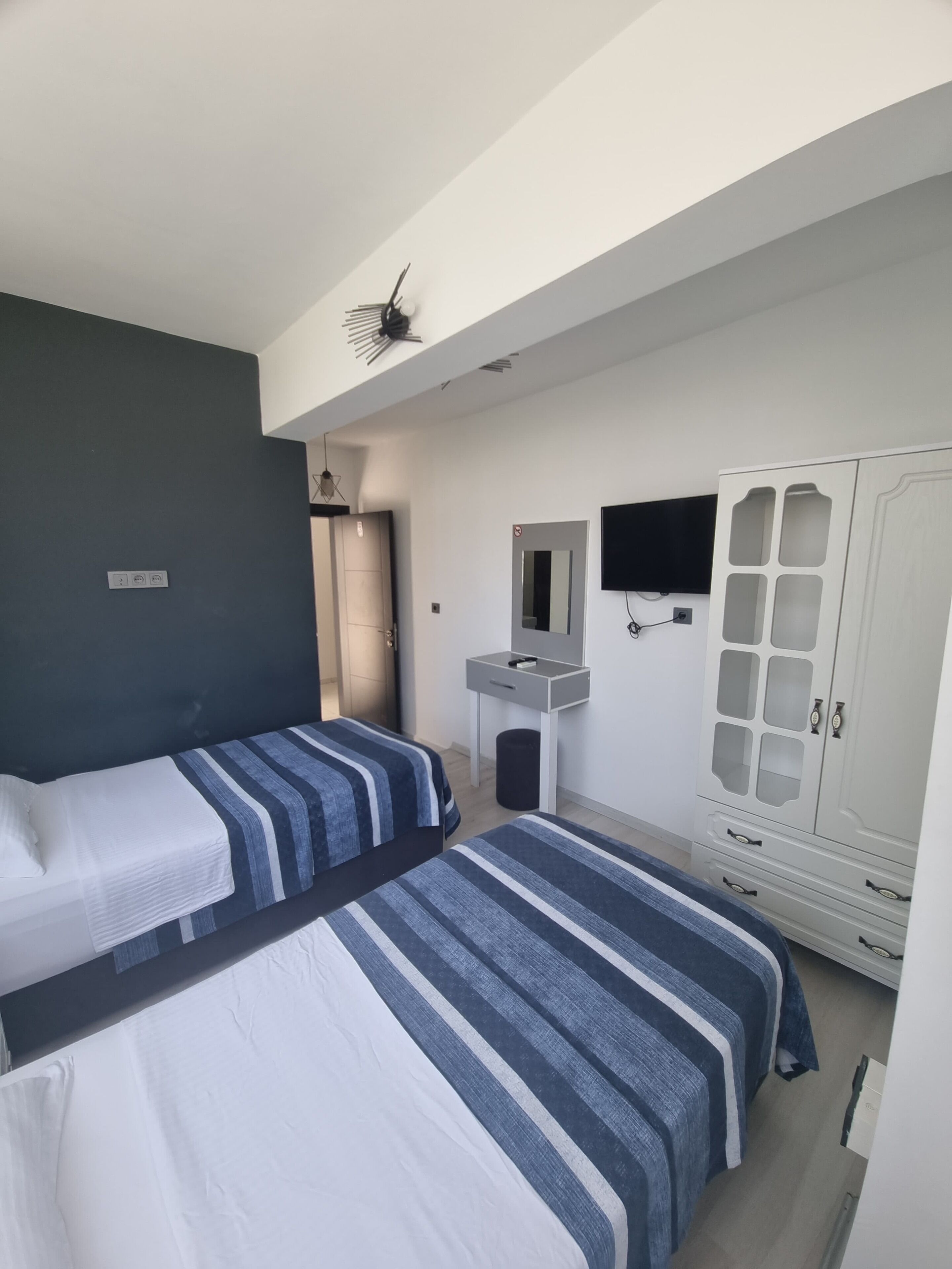 A hotel room with two beds, a wardrobe, a mirror, and a television.