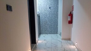 A hallway with white walls, a tiled floor, and a fire extinguisher on the right. - Kardelen Otel (Bodrum)