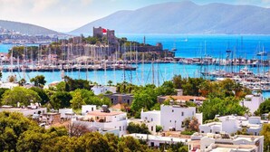 A coastal town with a marina filled with boats, historic buildings, and lush greenery. - Kardelen Otel (Bodrum)